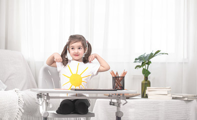 Obraz premium The girl is sitting at the table and doing homework. The child learns at home. Home schooling.