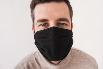 Young man in a black protective mask. Personal protective equipment for coronovirus. Homemade mask for access to public places