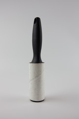 Dirty sticky roller for collecting dust and hair from clothes on a white background.