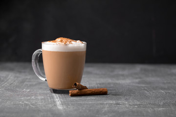 Side view of delicious cappuccino coffee with milk foam sprinkled with cinnamon in a transparent...