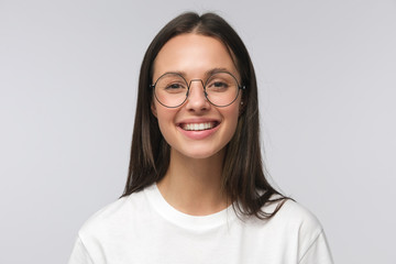 Young laughing woman wearing big round eyeglasses, smiling happily, reacting to joke, looking...