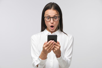 Young woman with shocked face staring at screen of her phone, winning something unexpectedly,...
