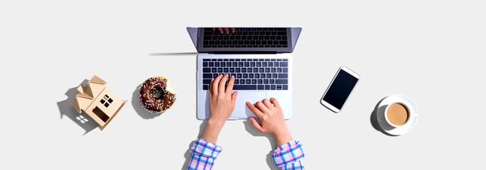 Woman using a laptop computer with a donut and a cup of coffee