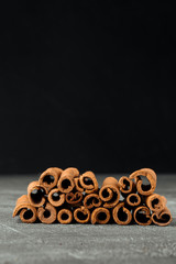 Closeup side view on brown natural fragrant cinnamon sticks on the grey background, vertical format
