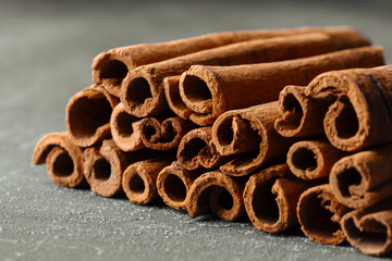 Closeup side view on brown natural fragrant cinnamon sticks on the grey background, horizontal format