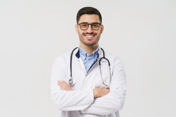 Fototapeta premium Portrait of smiling handsome male doctor with stethoscope around neck, wearing white coat and round glasses, isolated on gray background