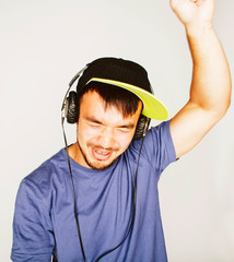 young asian man in hat and headphones listening music on white background