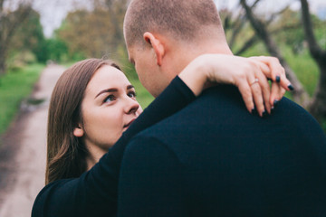 couple in blue jeans and black shirts in a green park