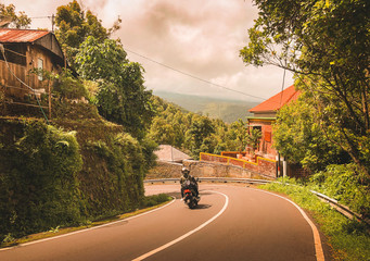 Person fährt mit Motorroller eine Serpentine in Bali, Indonesien