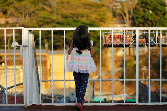 Rear View Of Girl Standing By Railing Against Trees