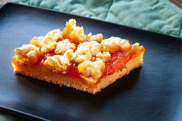 Homemade apricot pie. Slice of rustic hot sweet pie on a black plate. Natural organic food. Selective soft focus.