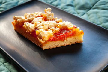 Homemade apricot pie. A slice of rustic hot sweet pie on a black plate. Natural organic food. Selective soft focus.