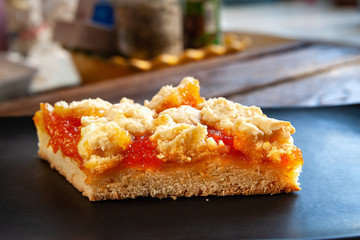 Home-made cake with apricots. Slice of rustic hot sweet pie on a black plate on a wooden background. Natural organic food. Selective soft focus.