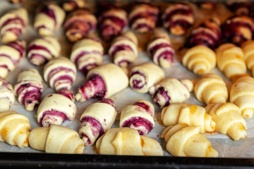 Grandmother making handmade tasty butter rolling cookies with fruit and berry jam on oven tray before baking at kitchen indoor. Rolled spin homemade healthy pastry preparing