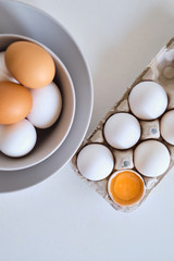 Chicken eggs on minimalist plates. Art photo with uncooked eggs on white table. Natural organic farm product. Preparing for Easter holiday. Kitchen art, dish on cuisine. Raw ingredient for cooking eat