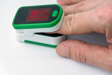 Pulse Oximeter portable digital device to measure person's oxygen saturation. Reduction in oxygenation is an emergency sign, heavy form of Covid-19 viral pneumonia. Device on a Caucasian male hand.