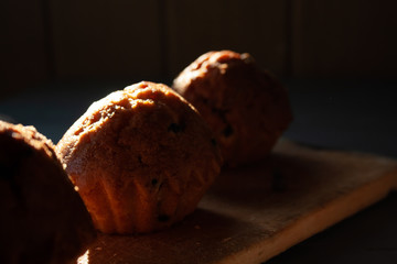 Fresh muffins with chocolate lie on a wooden board, top view.