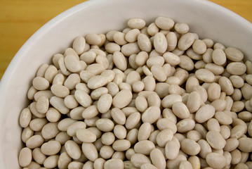 White bowl filled with white beans served on wooden table