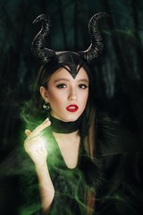 Stock Photo - Maleficent demonic. Girl dressed as a fairy witch in raincoat and with horns