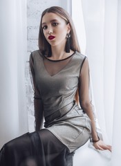 Portrait of beautiful young brunette girl with makeup  in grey fashion clothes 