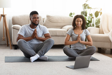 Quarantine trainings. Happy african american couple practicing yoga online with laptop - Powered by Adobe