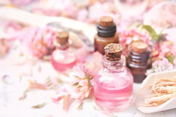 Obraz na płótnie Canvas Essential oil bottles on pink clover flowers and medicinal herbs background, shallow DOF, toned