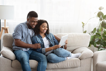 Quarantine Leisure. Happy Black Couple Relaxing With Digital Tablet At Home
