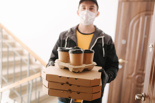 First persom view of delivery man in mask and gloves give pizza and coffe. Stay home