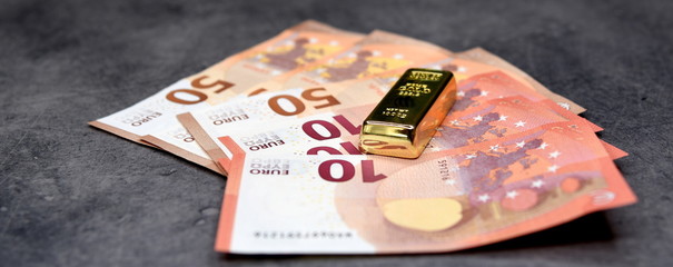 Kleiner, glänzender Goldbarren auf  Euro-Geldscheinen