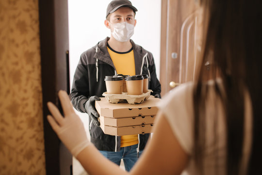 Delivery man in mask and gloves give pizza and coffe to customer. Stay home