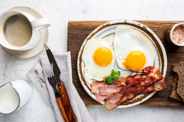 Fried eggs and bacon for breakfast on a plate, top view, copyspace