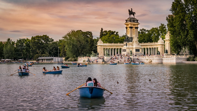 Pond in Retiro Park. Boats, King Alfonso XII monument and people spending free time. 