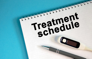 Fototapeta premium TREATMENT SCHEDULE - text on a notepad. Lie a pen and a medical thermometer