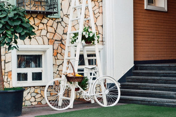 Fototapeta na wymiar White bicycle with a basket in front of house
