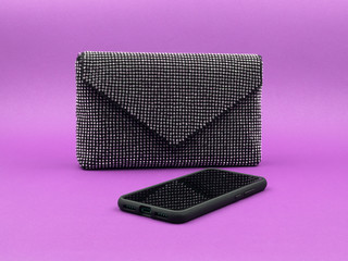 A glamorous handbag and mobile phone on a purple background.