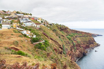 View of the coast of Madeira and the village of Pontu de Garageu on a cloudy summer day.