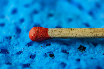 Red match head on a blue, textured background.