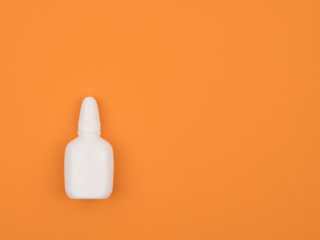 Nasal spray on orange background close-up. The view from the top.