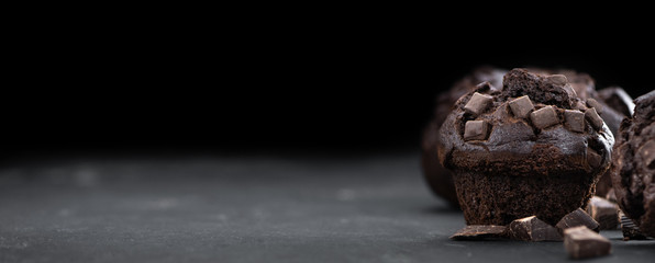 Fresh made Chocolate Muffins on a slate slab (close-up shot; selective focus)