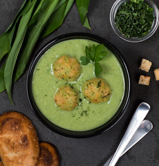 Cream soup of greens with meatballs with croutons in a bowl on a dark background top view
