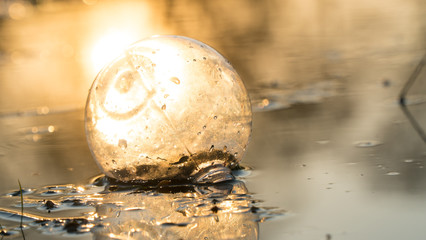 glass ball on the hand, against the backdrop of a beautiful sunset. Sunset water. Reflection in water