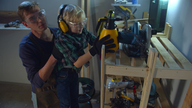 The Boy Is Trying To Reach The Top Shelf, And Dad Helps Him