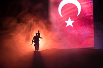 Naklejka na ściany i meble Silhouette of soldier with rifle against a turkish flag. Selective focus