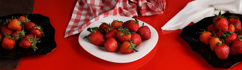 Panorama with strawberries on white and black plates