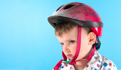 Boy in a protective helmet on a blue background. Safety, child.