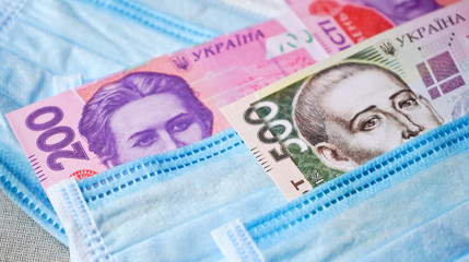 Medical masks with money. Ukrainian money with protective masks. A fan of Ukrainian hryvnia with a fan of medical masks.