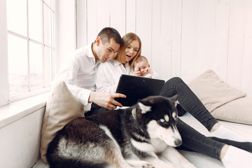 Cute family in a room. Lady in a white shirt. Family sitting with tablet.