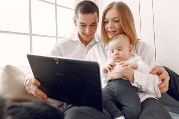 Cute family in a room. Lady in a white shirt. Family sitting with tablet.