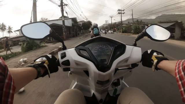 Man riding on scooter over Samui streets in Thailand. Time lapse of travelling over the high-road in the city. Theme of travelling on vehicle over Thailand during vacation journey.
