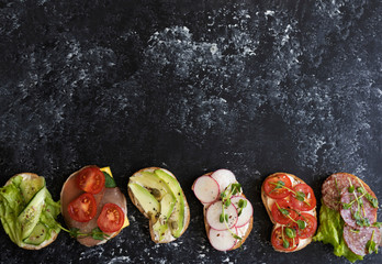 Bright sandwiches on a dark background, vegan and meat fillings on tapas decorated with...